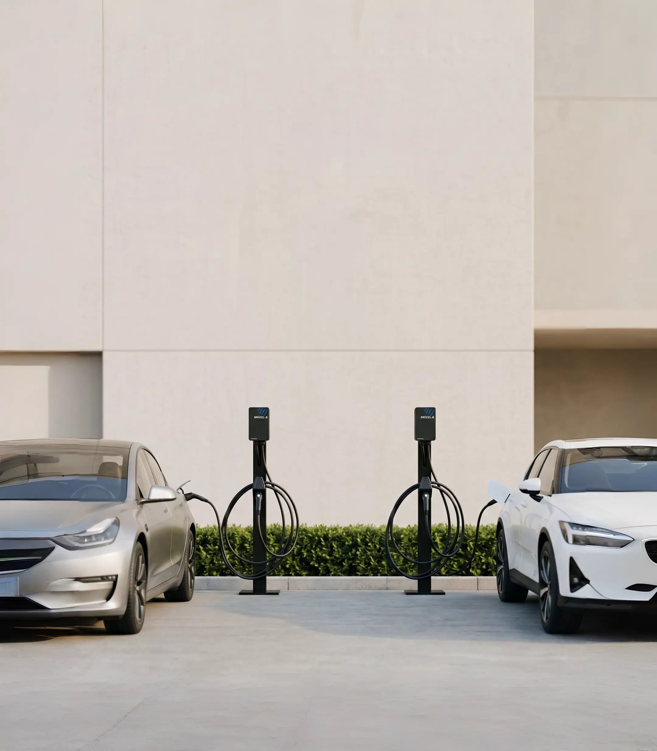 Two Grizzl-E EV chargers installed side by side in a driveway, each charging an electric vehicle.